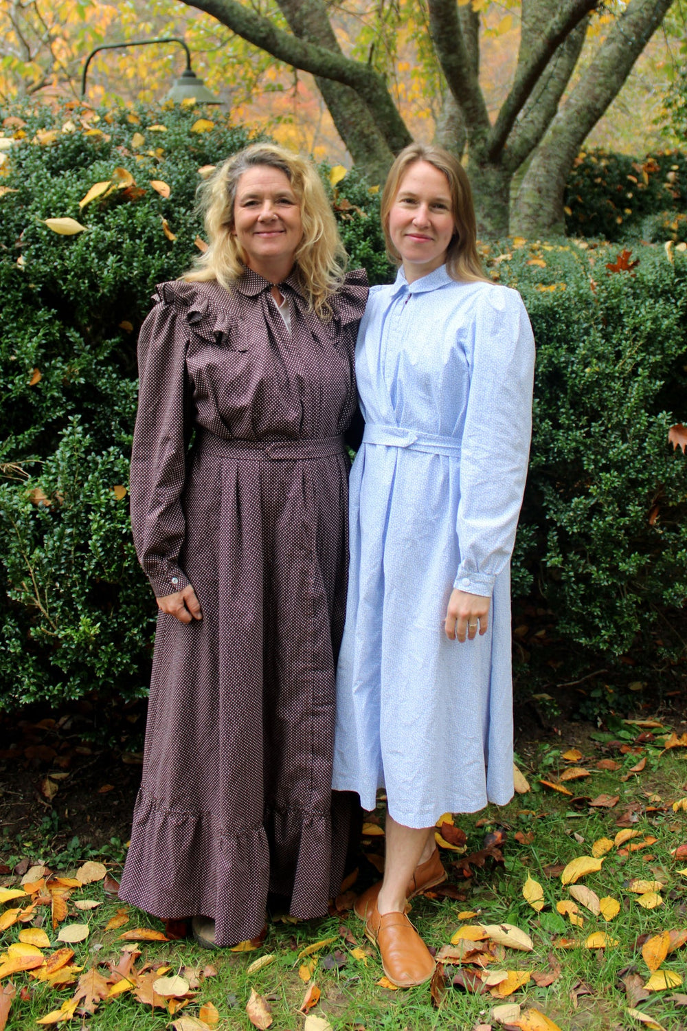 Women wearing the 246 Calico Day Dress sewing pattern from Folkwear on The Fold Line. A vintage-inspired dress pattern made in lightweight cotton and blends, silk, lightweight wools, or rayon fabric, featuring a collar, optional rounded yokes with ruffles, buttoned front lining, pleats at the centre front, princess seams at the back, full sleeves gathered at the top and finished with cuffs, optional hem flounce, and maxi or midi length.