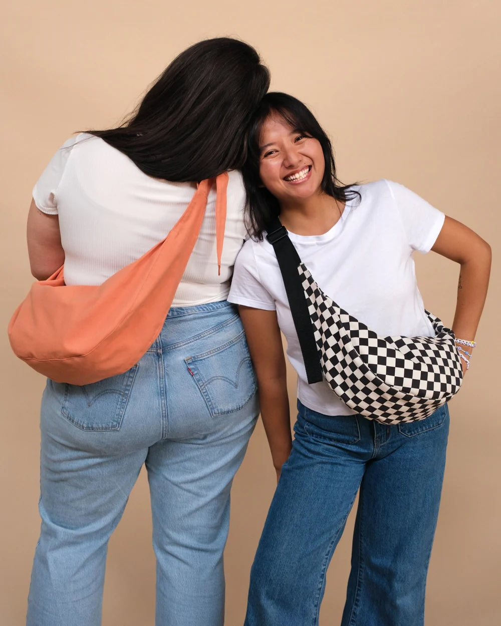 Women wearing the Bestie Bag sewing pattern from BF Patterns on The Fold Line. A cross-body bag pattern made in denim, canvas, twill, heavyweight nylon, ripstop, leather, or vinyl fabric, featuring a banana shape, flat or pleated front, zip closure, and webbing or fabric strap.