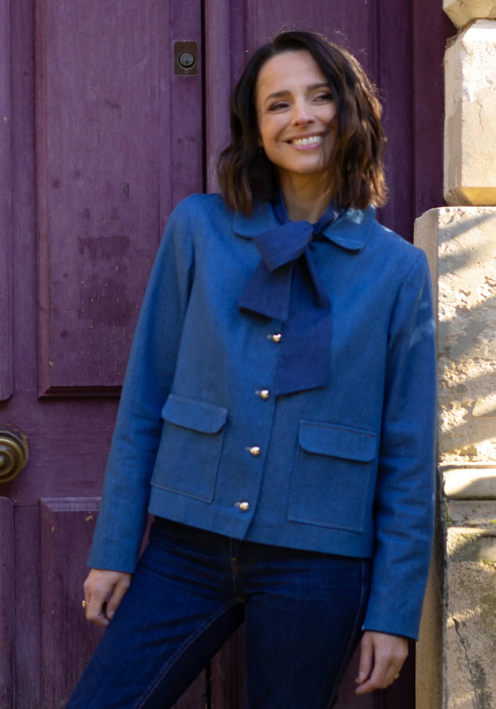 Woman wearing the Calypso Jacket sewing pattern from Maison Fauve on The Fold Line. A hip-length jacket pattern made in wool, jacquard, tweed, denim, or gabardine fabric, featuring a collar, patch pockets with flaps, gathered back, and full lining.