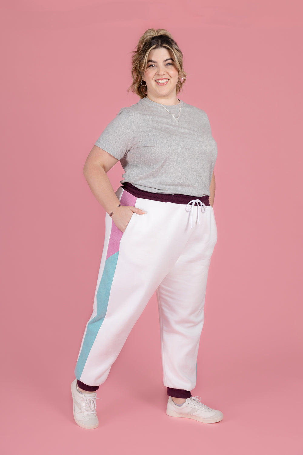 Woman wearing the Cece Joggers sewing pattern from Tilly and the Buttons on The Fold Line. A joggers pattern made in sweatshirt fleece or French terry fabric, featuring a relaxed fit, mid-rise elasticated waistband with a drawstring, and colour-blocked side panels with pockets.