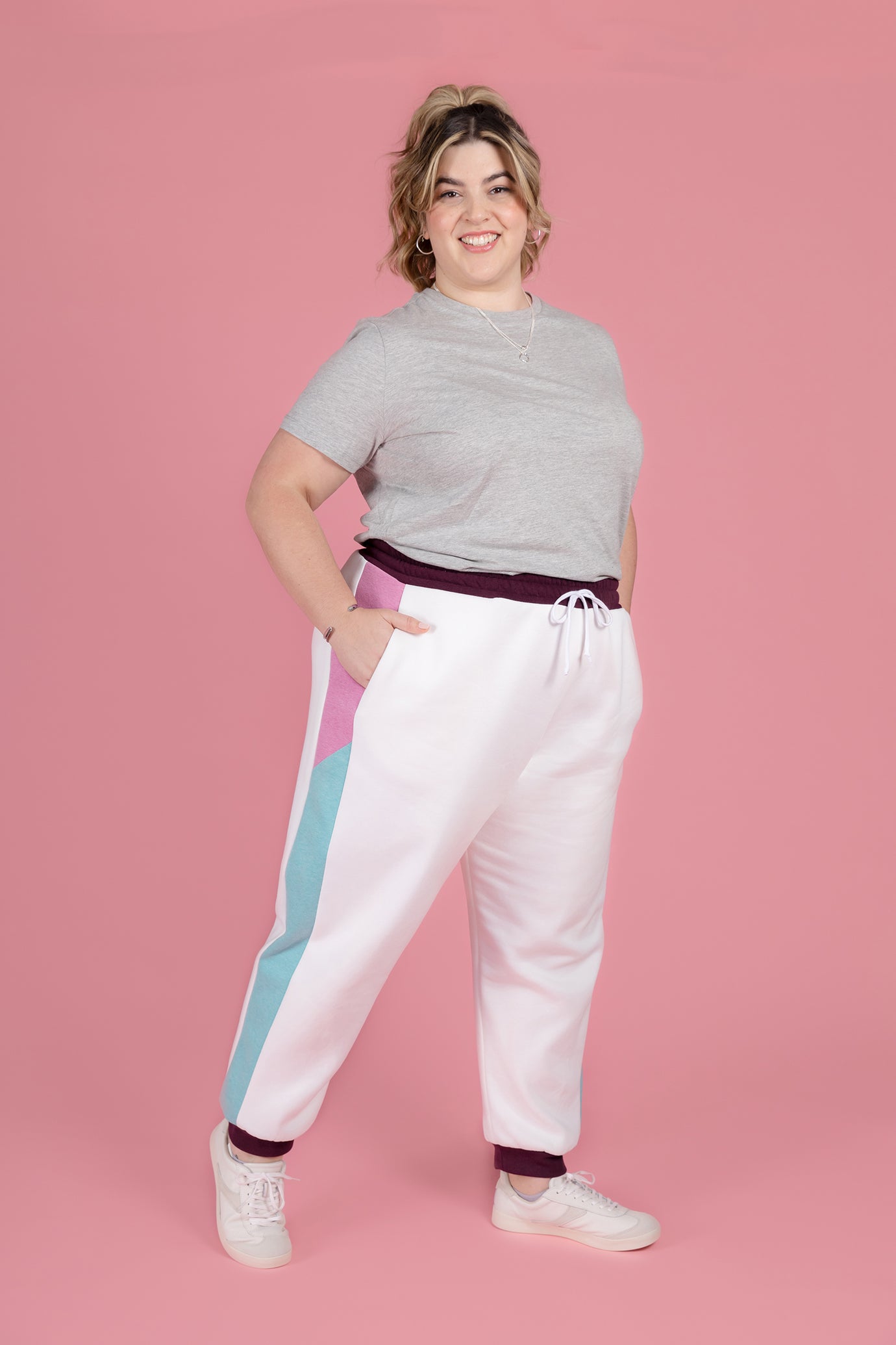 Woman wearing the Cece Joggers sewing pattern from Tilly and the Buttons on The Fold Line. A joggers pattern made in sweatshirt fleece or French terry fabric, featuring a relaxed fit, mid-rise elasticated waistband with a drawstring, and colour-blocked side panels with pockets.