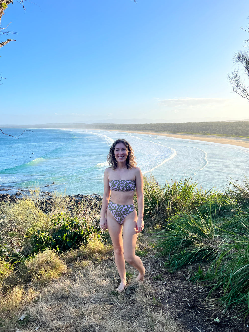 Woman wearing the Easties Bikini sewing pattern from Elle Stitch on The Fold Line. A bikini pattern made in swim tricot fabric, featuring a curved bandeau top and high-waist, high-leg bottom with a cheeky back.
