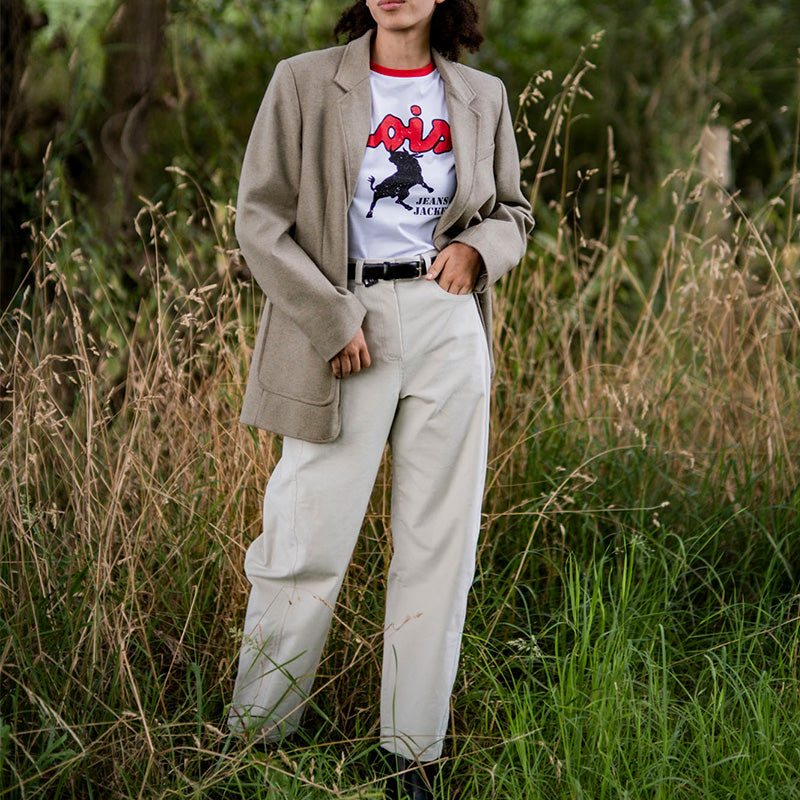 Woman wearing the Gizeh Trousers sewing pattern from Fibre Mood on The Fold Line. A trousers pattern made in corduroy, velvet, denim, cotton twill, woven jacquard, or leather(ette) fabric, featuring a fly front, side front pockets, back patch pockets, horizontal darts in the back, balloon leg, and ankle length.