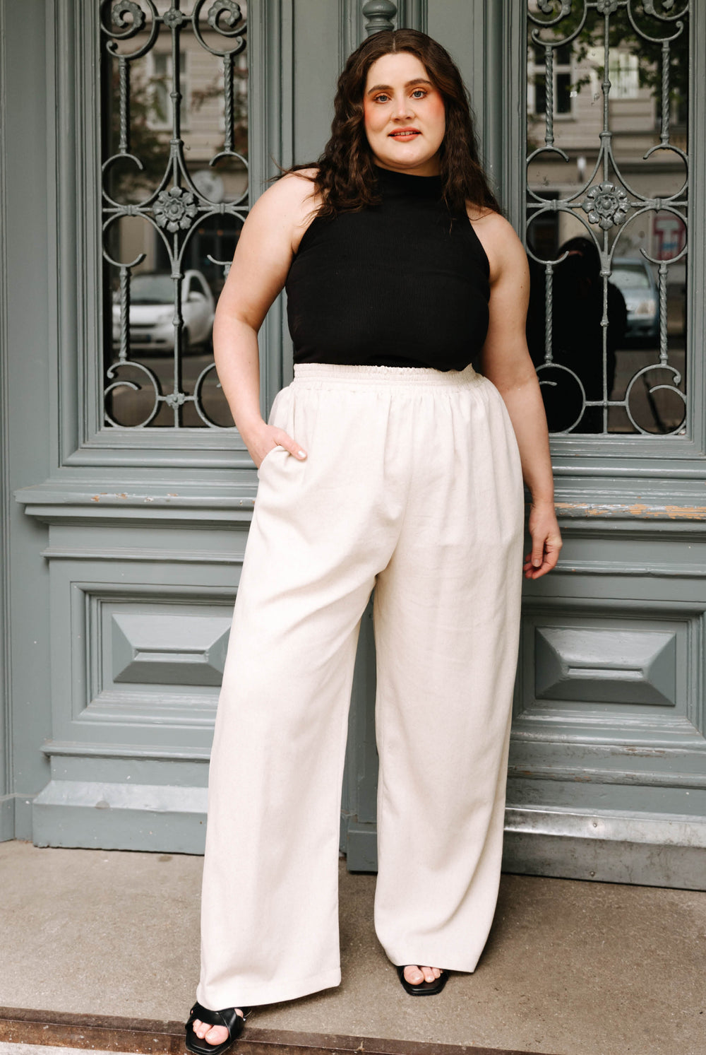 Woman wearing the Lana Pants sewing pattern from JULIANA MARTEJEVS on The Fold Line. A pants pattern made in linen or cotton fabric, featuring an elastic waistband, wide legs, and pockets.