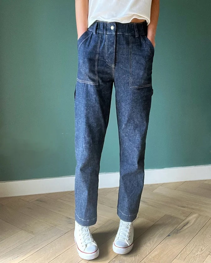 Woman wearing the Langston Trousers sewing pattern from French Navy on The Fold Line. A trousers pattern made in linen, cotton twill, denim, or corduroy fabric, featuring a mid-rise relaxed fit, slightly tapered leg, elasticated waistband, fly front, pockets, and carpenter details.
