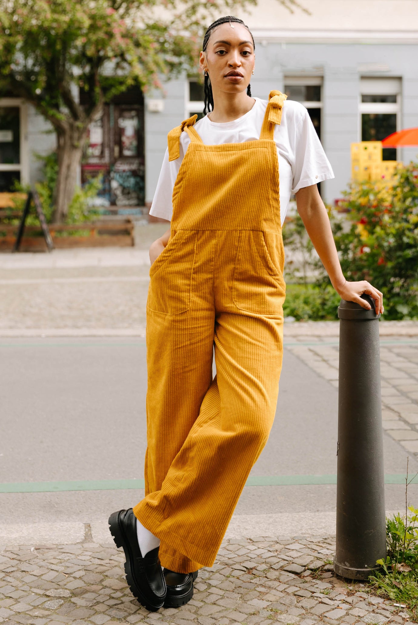Woman wearing the Maisie Overalls sewing pattern from JULIANA MARTEJEVS on The Fold Line. A dungaree pattern made in denim or corduroy fabric, featuring a relaxed fit, adjustable tie straps, and pockets.
