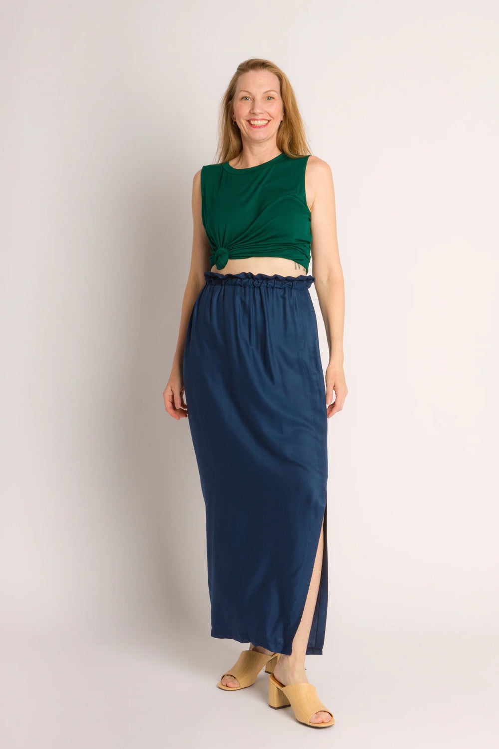Woman wearing the One Hour Skirt sewing pattern from Cris Wood Sews on The Fold Line. A skirt pattern made in cotton, linen, gauze, viscose, cupro, rayon, or silk fabric, featuring a straight silhouette, elastic waistband with a ruffle effect, front slit, and ankle length.