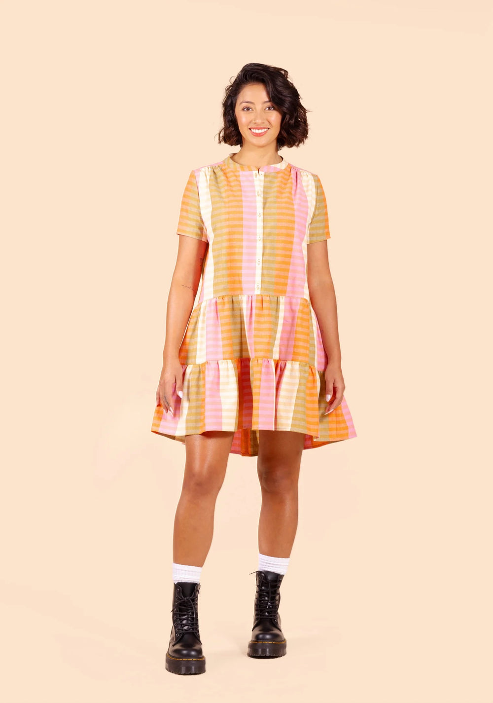 Woman wearing the Poppy Dress sewing pattern from Grainline Studio on The Fold Line. A dress pattern made in cotton lawn, voile, rayon, viscose, or linen fabric, featuring a round neck with a band collar, button front, short sleeves, two gathered tiers, and a mini length.